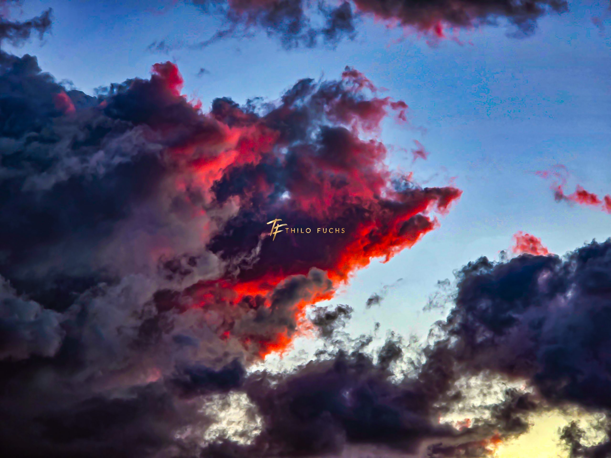 Zwischen Dunkelheit und Licht: Ein Abendhimmel in fünf Momenten Dunkle Wolken mit intensiv rot beleuchteten Kanten vor blauem Abendhimmel.