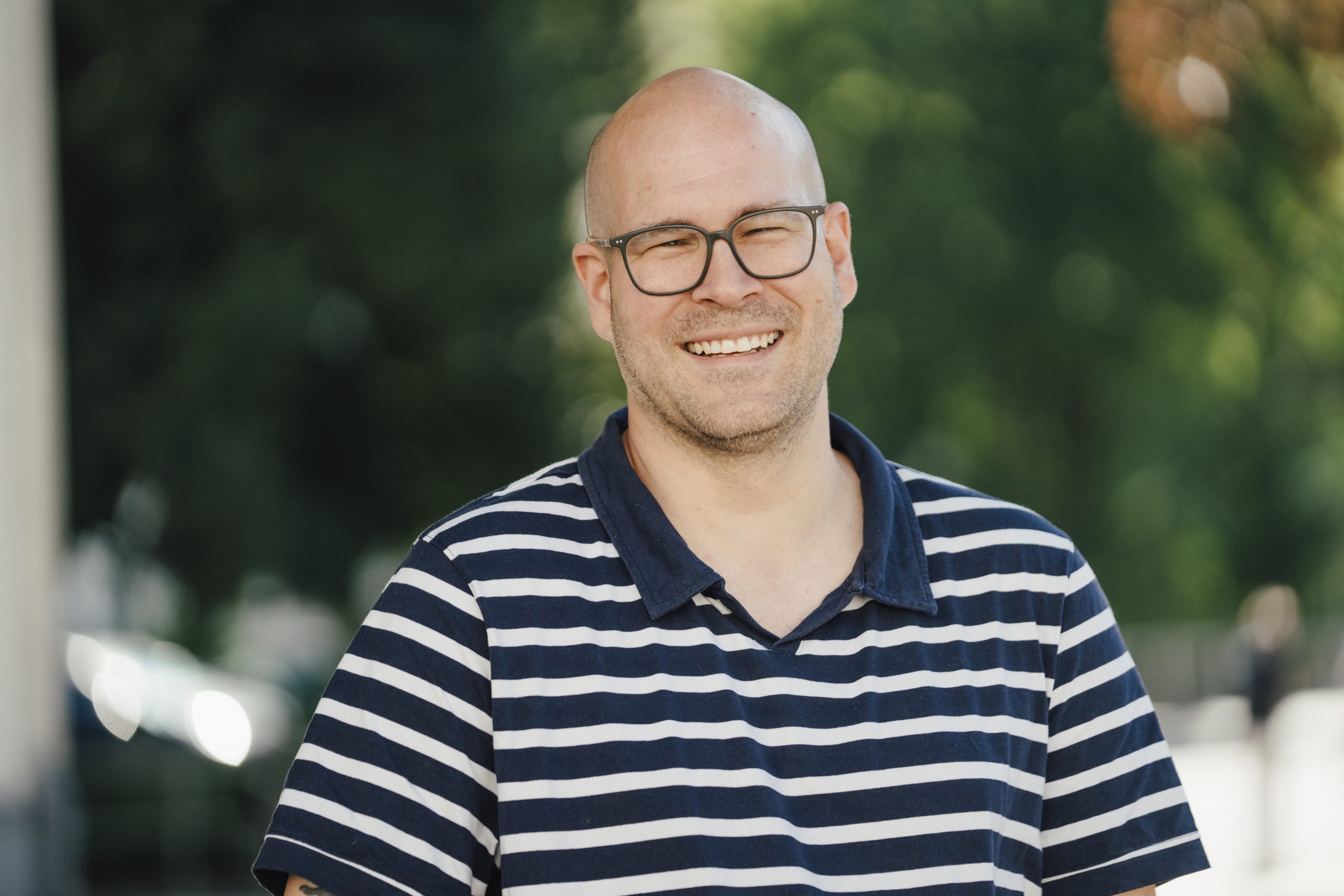 Thilo Fuchs lächelt vor einem weichen grünen Hintergrund.